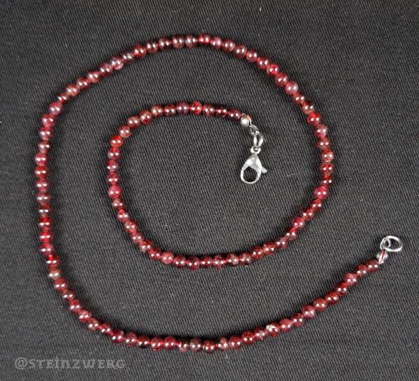 Kugelkette aus Granat mit silberfarbenem Karabinerverschluss.